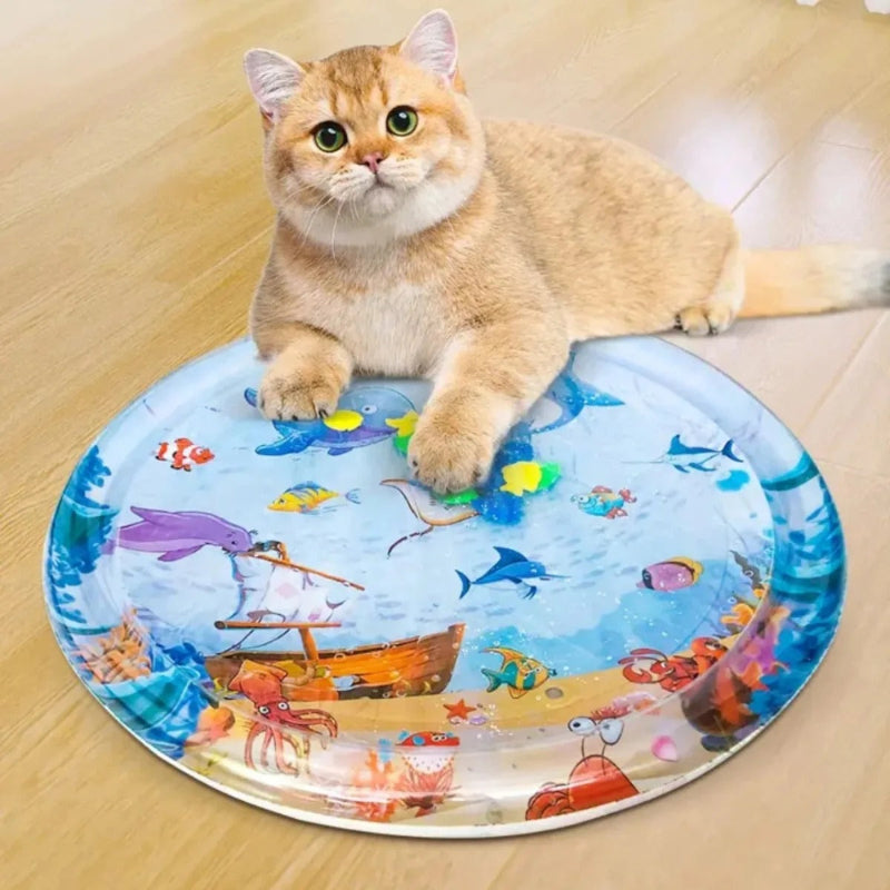 Coussin à chat attractif avec des dessins de poissons et de ce qui concerne la mer avec un chat beige qui est assis à cÎté de ce coussin.