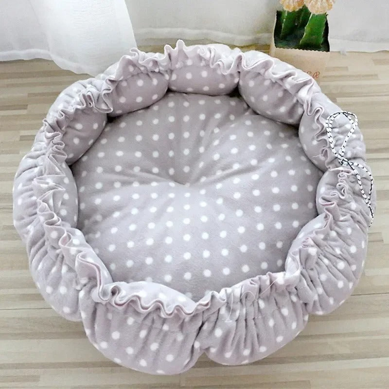 Un coussin chat en forme de nid avec un serrage tout le tour beige avec des motifs de pastilles blanches.