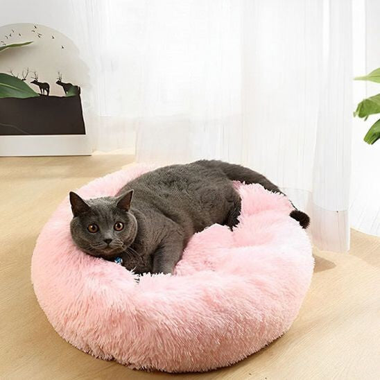 Coussin chat de couleur rose clair en peluche douce avec un chat noir allongé dessus.