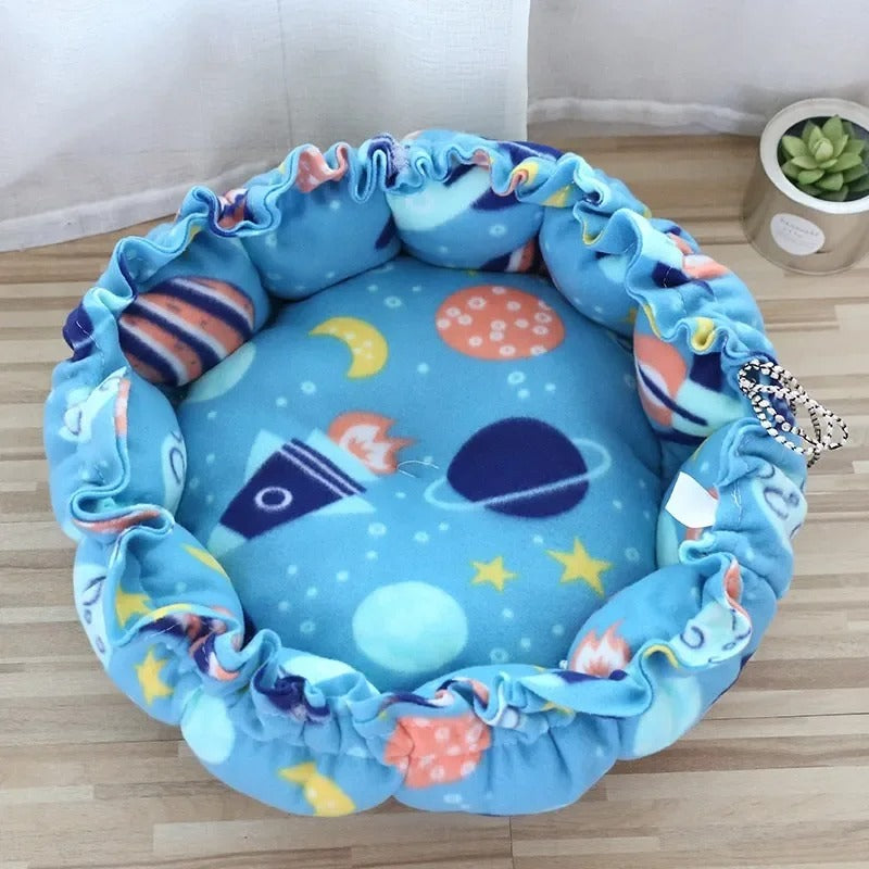 Un coussin chat en forme de nid avec un serrage tout le tour bleu avec des motifs de planĂštes.
