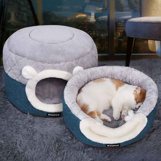niche à chat ronde en forme de pouf moitié en hat grise et en bas bleu-vert en deux positions, ouverte et pliée, avec un chat roux et blanc qui dort sur cette niche.