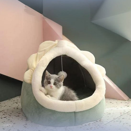 Niche pour chat en forme de licorne large et verte avec une balle suspendue et un chaton gris assis dedans