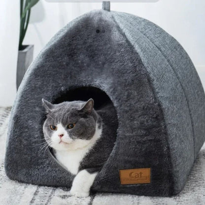 Maison pour chat en forme de petite niche grise avec un chat gris qui est sur le point de sortir de cette maison.