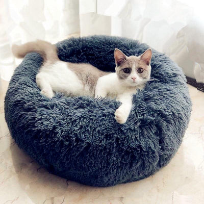 Coussin à chat bleu marine en peluche avec un chat blanc et gris assis dedans.