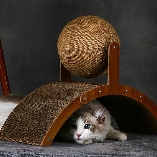 Grattoir chat en bois marron en forme de pont avec une boule en sisal placée dessus et un chat qui se cache en dessous.