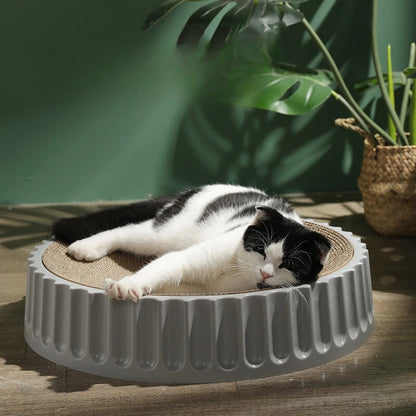 un-chat-blanc-et-noir-qui-dort-sur-un-griffoir-à-chat-rond-avec-une-base-blanche-robuste