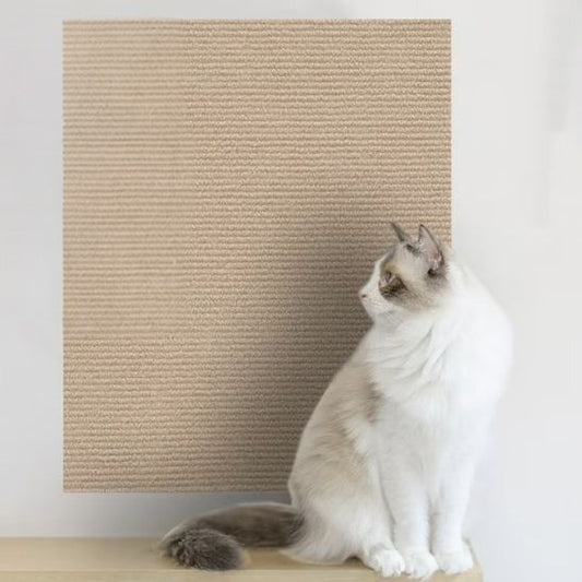 Un chat blanc assis à côté d'un griffoir à chat beige collé sur un mur.