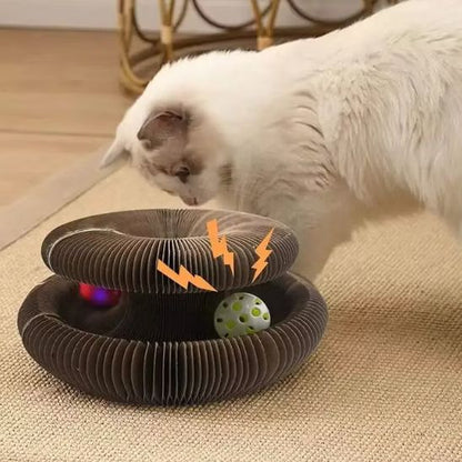 Un griffoir chat carton marron rond avec un espace entre le haut et le bas et une balle qui roule dans cet espace avec un chat blanc qui joue avec.