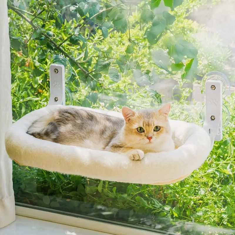 Un chat blanc avec du gris allongé sur un hamac chat fenetre blanc attaché avec des ventouses.