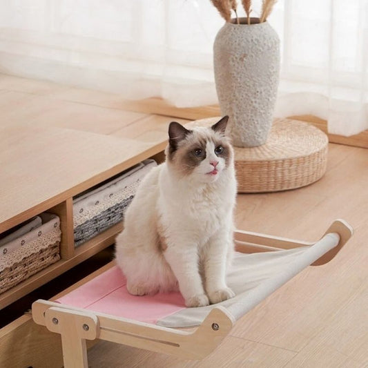 Un Sacré de Birmanie assis sur un hamac chat gris et rose accroché à un tiroir de table de salon et en attachement une image du même chat qui dort sur un hamac accroché à un lit.