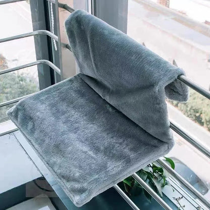 Un hamac chat gris placé sur un bord d'un balcon de maison.