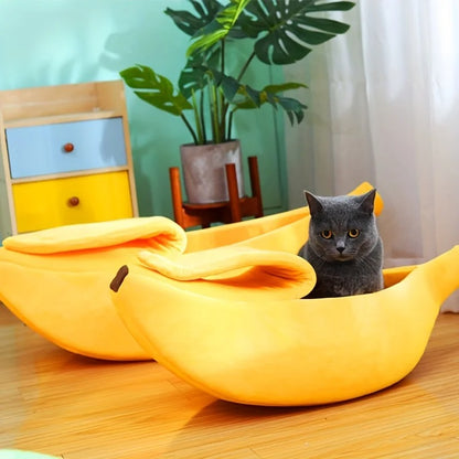 Lit pour chat petit et grand en forme de banane jaune avec un chaton gris foncé assis dedans.