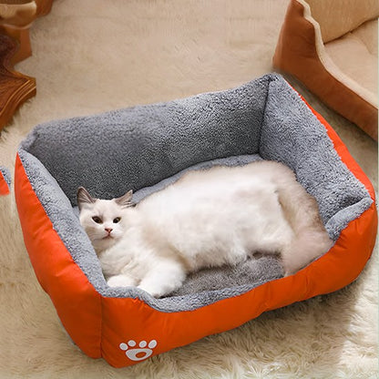 Lit pour chat rectangulaire orange et peluche grise à l'intérieur avec un chat blanc allongé dessus.
