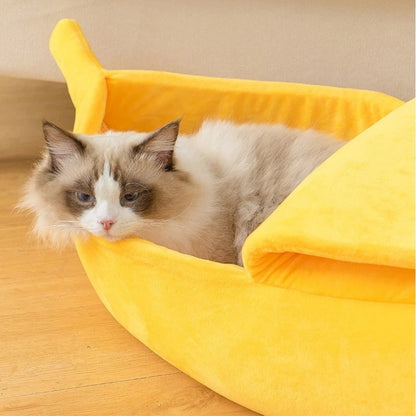 Lit pour chat en forme de banane jaune avec un chaton gris allongé dedans.