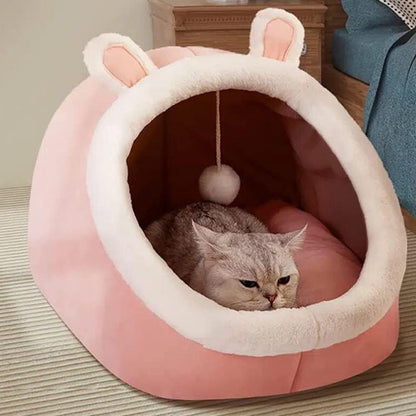 Niche chat forme d'oreilles de lapin rose et une balle suspendue avec un chat gris allongé dedans.