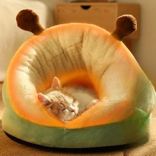 Niche chat en forme de pantoufle verte avec deux oreilles marron avec un chaton qui dort dedans et un contour orange montrant que cette niche est chaude.
