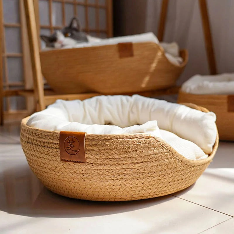 Panier osier chat beige avec un coussin blanc à l'intérieur.